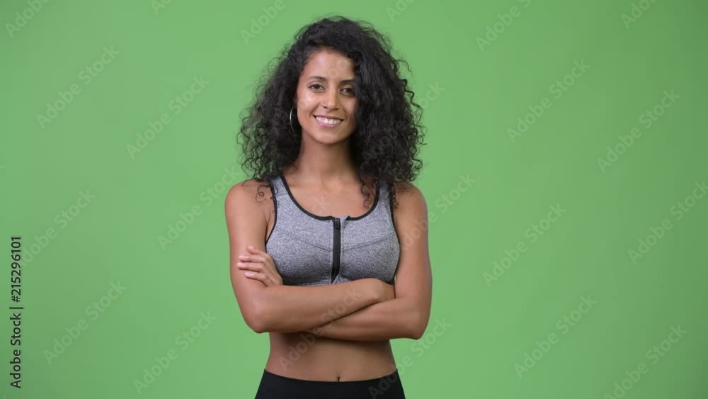 Young beautiful Hispanic woman with arms crossed ready for gym