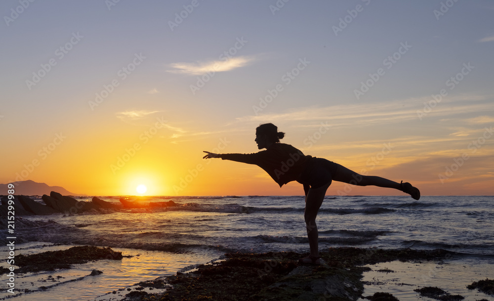 Girl dancing on the beach with the sun and the sea in the background, Sakoneta beach, Euskadi
