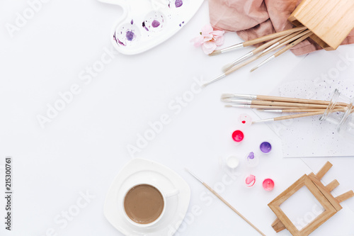 Flat lay composition with brushes, watercolour set and coffee cup on white background. Workspace freelance designer