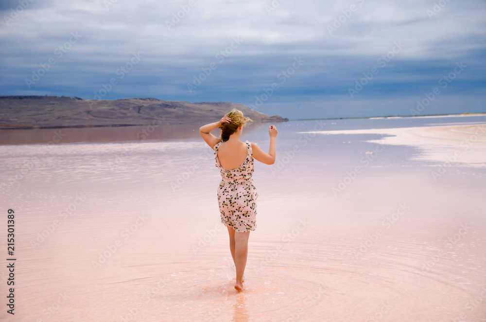 Woman walking on the salted shore of pink lake in Crimea