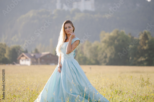 blond girl in blue dress infront of the castle