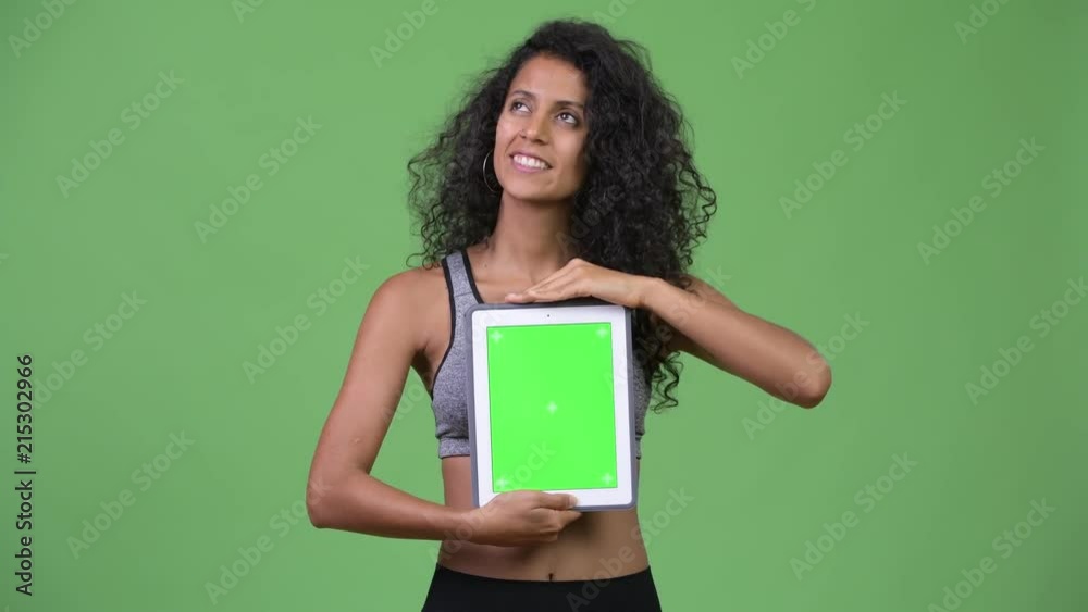 Young beautiful Hispanic woman with gym clothes showing digital tablet Young beautiful Hispanic woman with gym clothes showing digital tablet