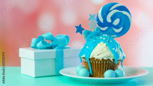 Blue theme colorful novelty cupcake decorated with candy and large heart shaped lollipops for children's or teen's birthday, Valentine's or Fatherr's Day celebrations. photo