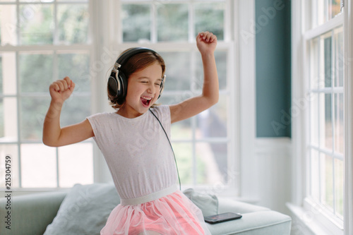 Cute young girl listening to music wearing headphones