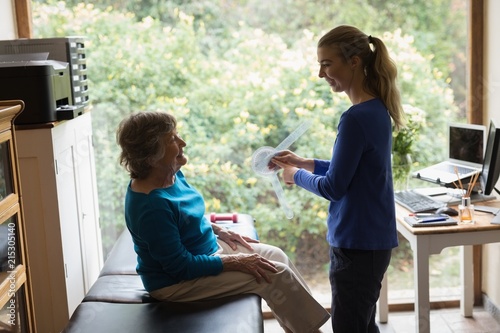 Physiotherapist showing goniometer reading to senior woman photo