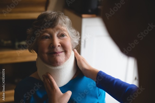 Physiotherapist setting cervical collar on senior woman