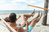 couple of tourists relaxing in hammock on beach near the sea