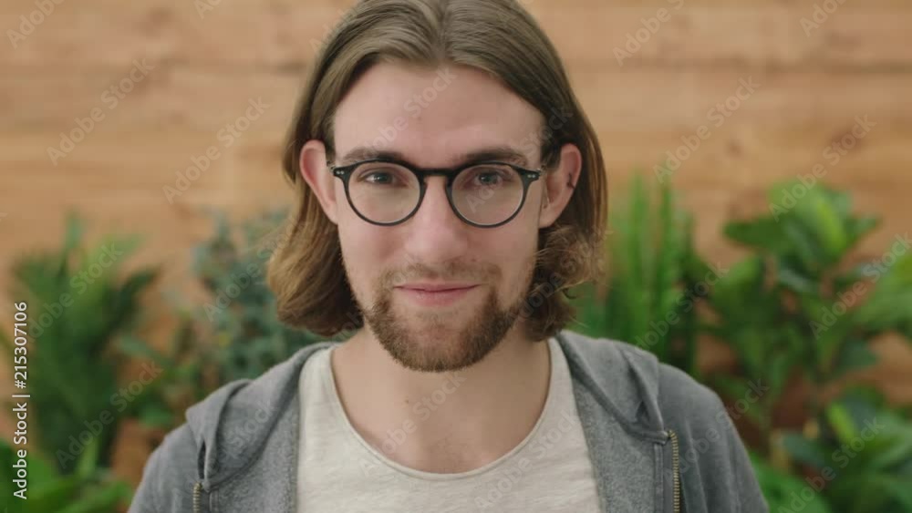 portrait of cute young geeky man puts on glasses smiling cheerful looking at camera portrait of cute young geeky man puts on glasses smiling cheerful looking at camera