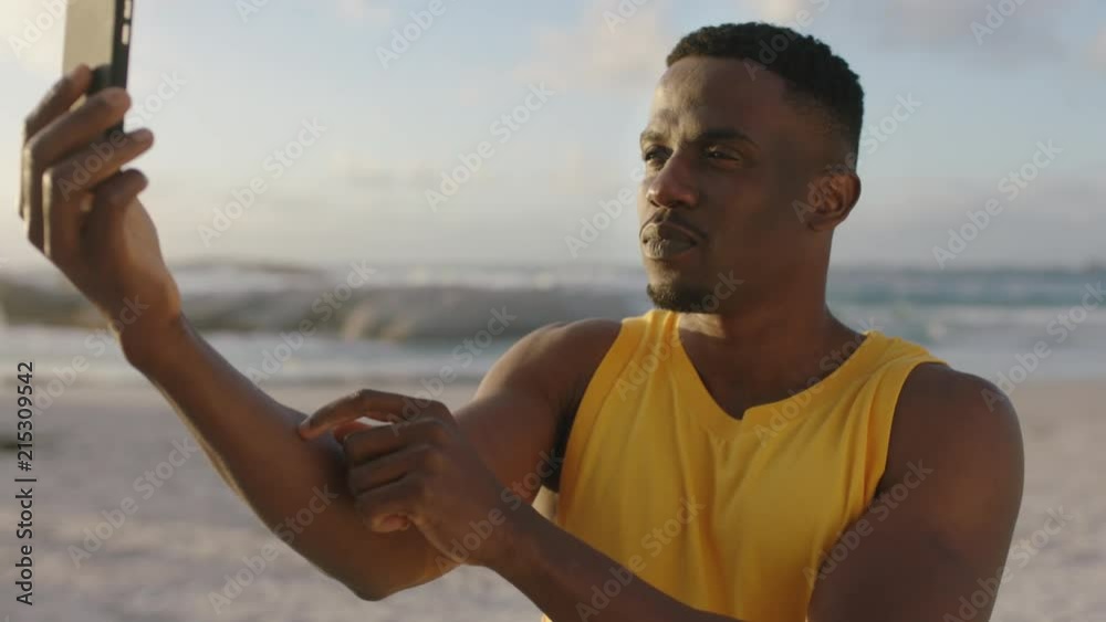 attractive young african american man taking funny selfie at beach using phone