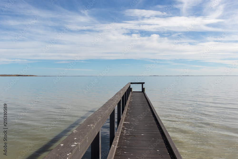 Small jetty with calm waters and blue skies