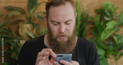 young caucasian man using smartphone portrait of bearded hipster browsing online looking pensive texting on mobile phone photo