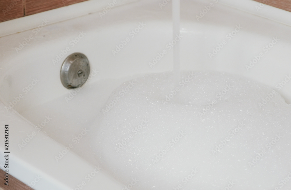Stream of water pouring into the bath with foam. Stream of water pouring into the bath with foam.