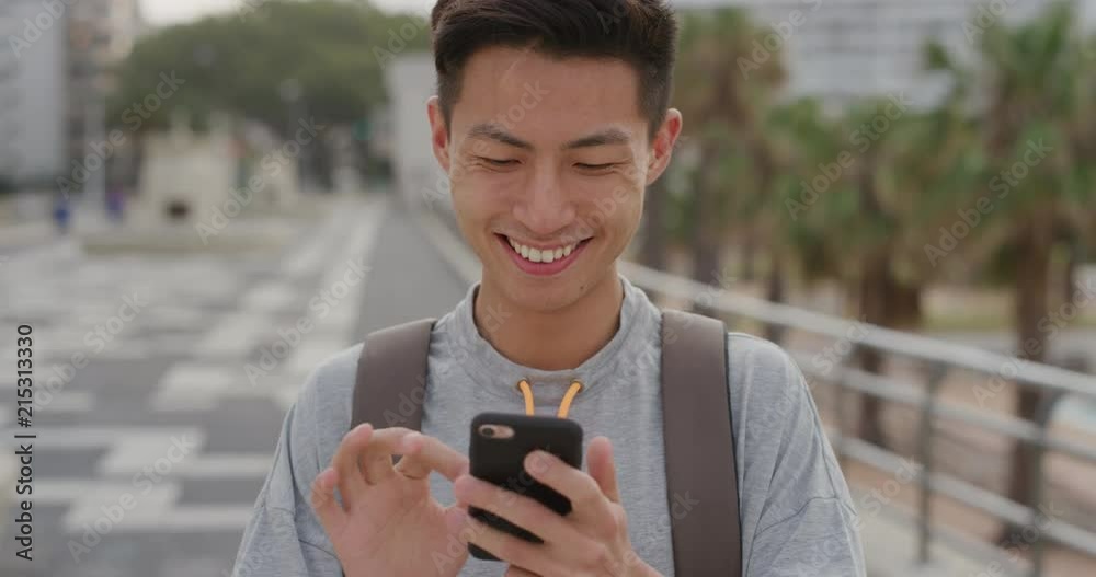 portrait young asian man teenager using smartphone texting enjoying messaging online sharing vacation on mobile phone communication technology smiling satisfaction urban background