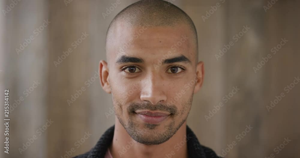 close up portrait of attractive young hispanic man smiling enjoying happy lifestyle looking at camera wooden background slow motion
