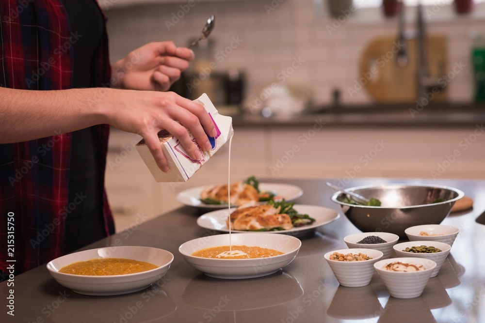 Woman pouring cooking cream in dal at home Woman pouring cooking cream in dal at home