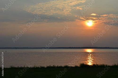 sunset through the clouds over a reservoir