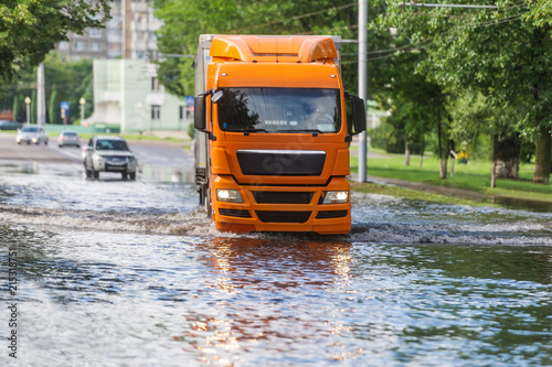 The large truck goes on the flooded city street after the strongest rain