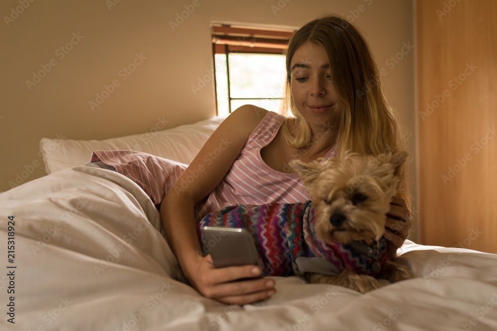 Girl with dog using mobile phone in bedroom Girl with dog using mobile phone in bedroom
