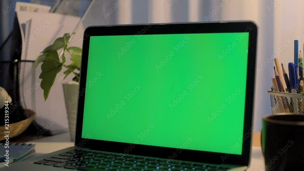 A laptop computer with a key green screen set on work office table. A laptop computer with a key green screen set on work office table.
