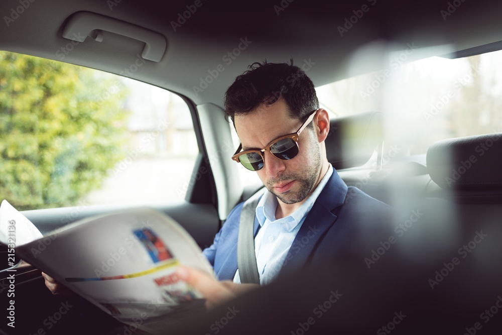 Businessman reading newspaper in a car Businessman reading newspaper in a car