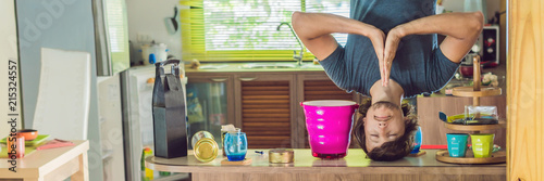 A man stands on his hands upside down in the kitchen BANNER, long format photo
