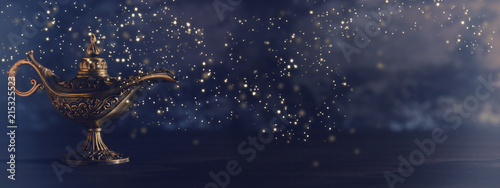 Photographie Image of magical mysterious aladdin lamp with glowing glitter lights over black background