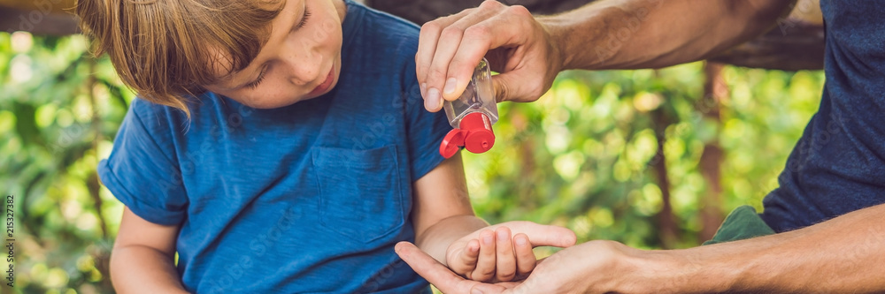 Father and son using wash hand sanitizer gel in the park before a snack BANNER, long format - obrazy, fototapety, plakaty 