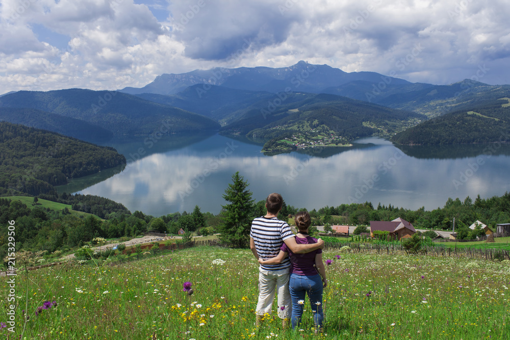 couple of man and woman enjoying the beautiful lake and mountain landscape. Bicaz, Romania