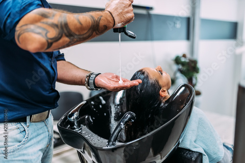 Beauty salon, hair care and people concept. Hairdresser washing customer hair with shampoo.