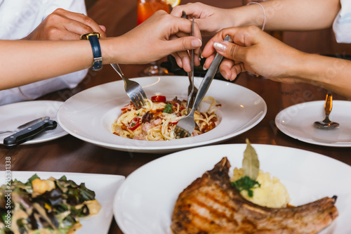 Close up of group of friends hands with a fork having fun eating and having italian dinner together.