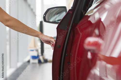 Woman hand on open the new red car door background © biggur