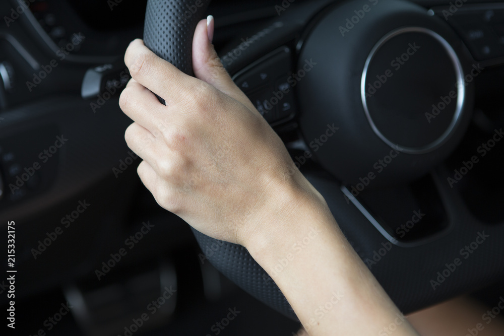 The hand of a girl with a stylish manicure lies on the handlebars in a saloon car.