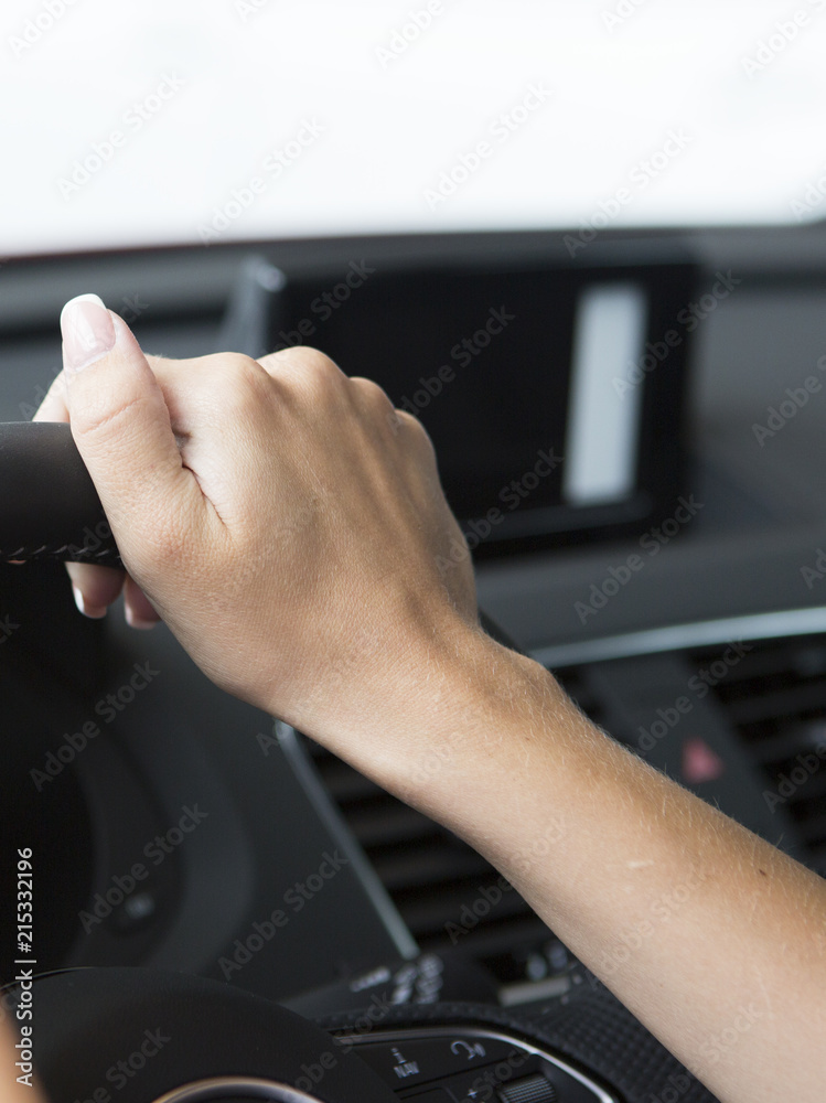 The hand of a girl with a stylish manicure lies on the handlebars in a saloon car.