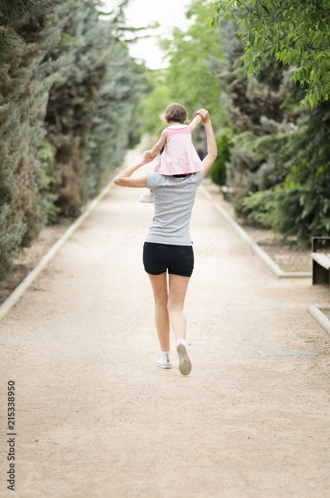 Little girl walking on the shoulders of her mother Little girl walking on the shoulders of her mother