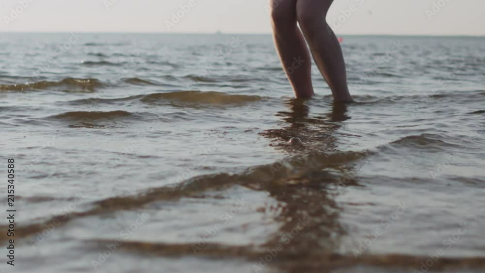 Slow motion handheld closeup of young female legs jumping in shallow water on a beach Slow motion handheld closeup of young female legs jumping in shallow water on a beach