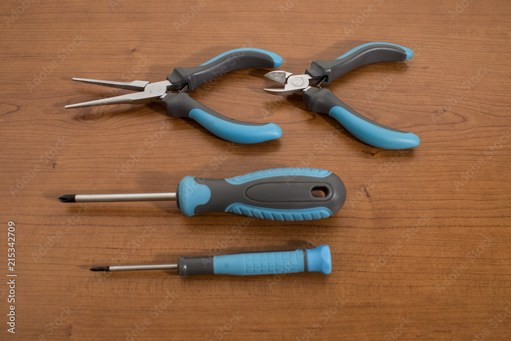 Tools, blue pliers and screwdrivers on a walnut table Tools, blue pliers and screwdrivers on a walnut table