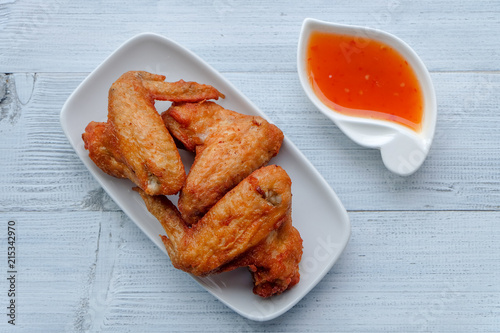Top view and close up: Deep Fried Chicken wing in white plate with sweet sauce on wooden background. Popular food for kids.