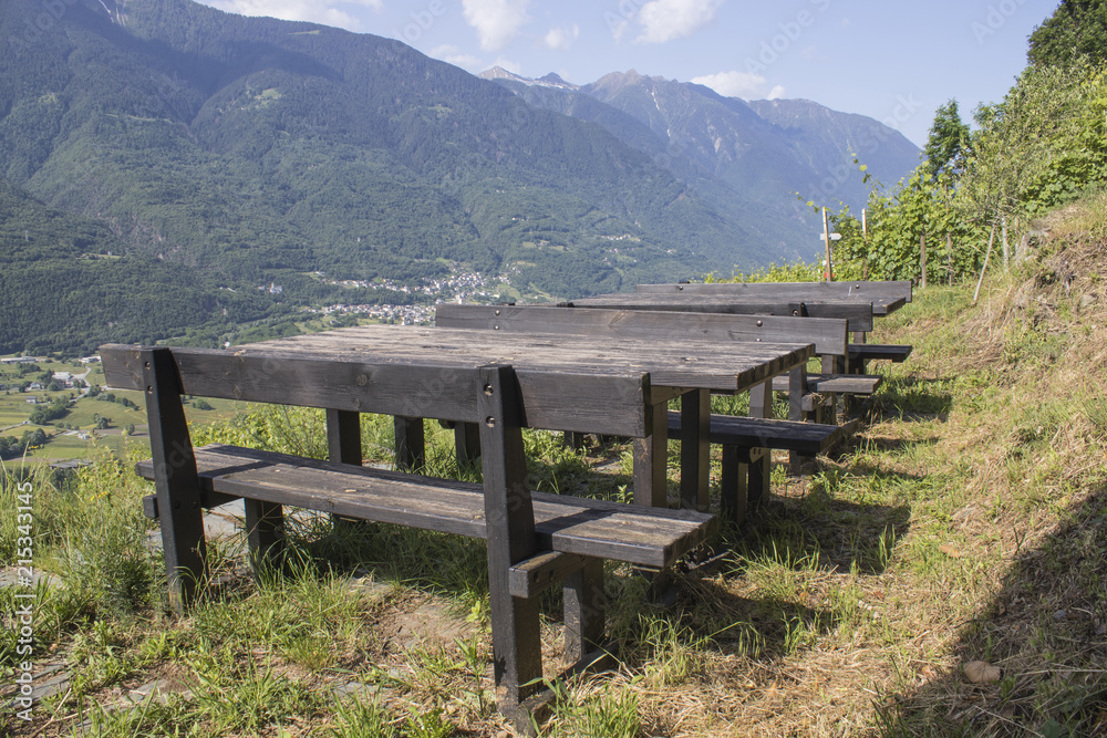 Wooden table in a park with mountains and blue sky