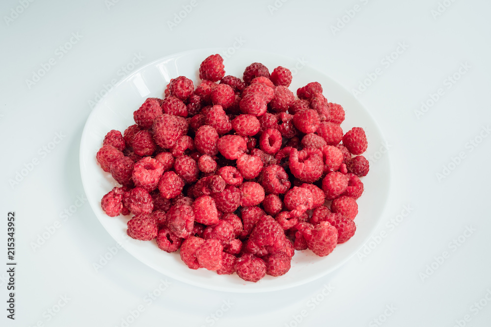Raspberry berries on a plate on a light background Raspberry berries on a plate on a light background