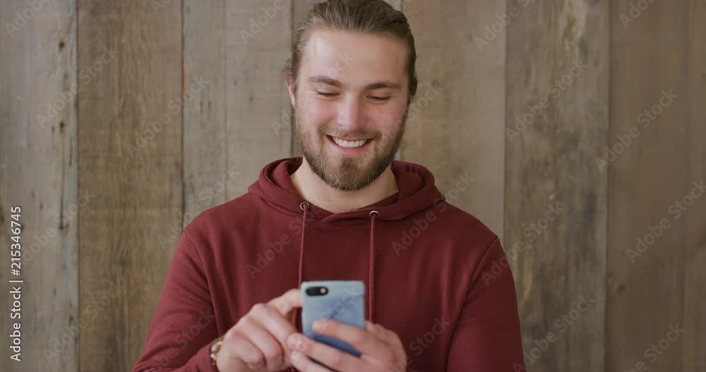 portrait of young man using smartphone texting browsing online enjoying sending sms messages mobile communication smiling happy slow motion portrait of young man using smartphone texting browsing online enjoying sending sms messages mobile communication smiling happy slow motion