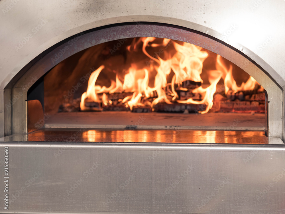 Fototapeta premium The working furnace for preparation of pizza. Inside burns firewood and big fire rises