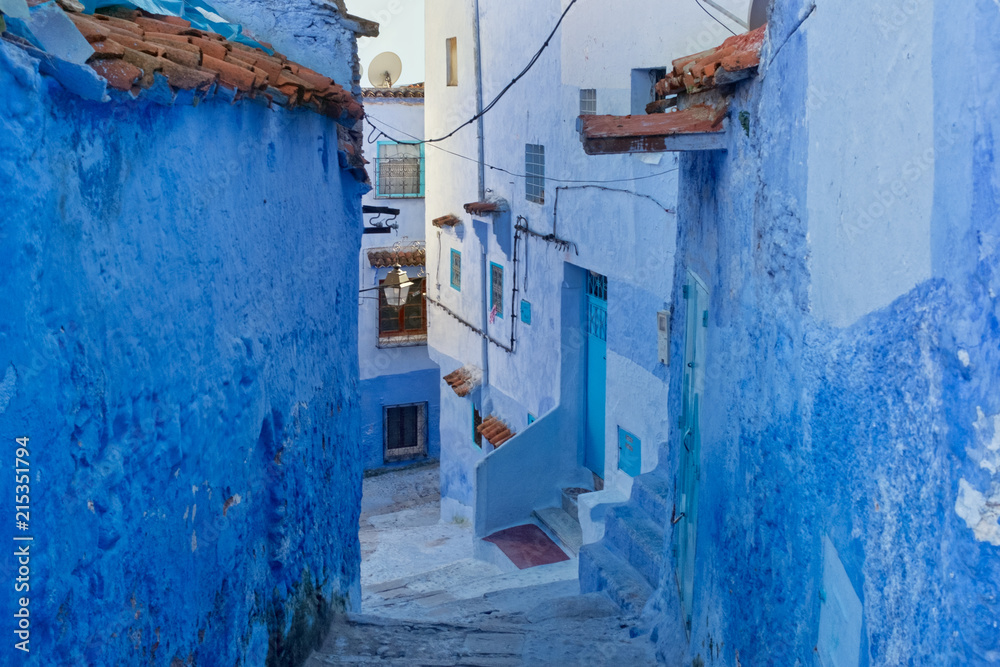 Narrow alleyway with steps and blue-washed houses in the old town of Chefchaouen, Morocco