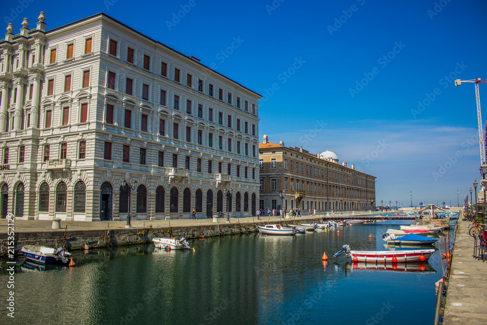 Italian old city street alley way with small river stream canal between buildings facade in bright colorful summer morning time and blue sky background