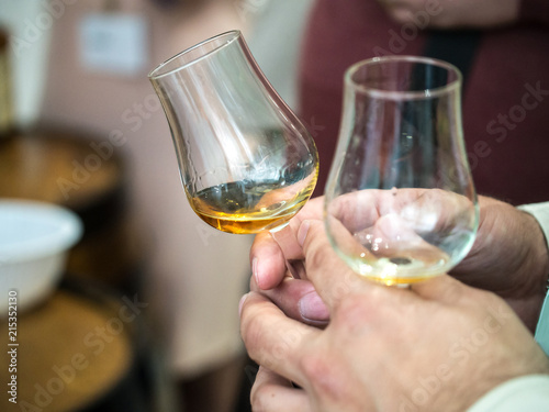 Hand holding a snifter glass filled with whisky