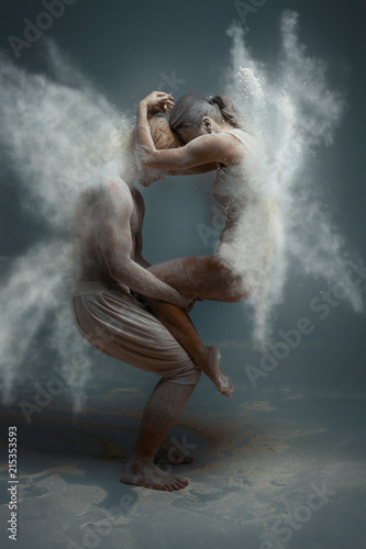 Fototapeta Naklejka Na Ścianę i Meble -  Dancing in flour concept. Girl woman female wearing white dress and guy man male making dance element in flour / white dust on isolated black / grey background. Fairy butterfly concept