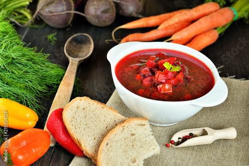 Healthy Borscht. National Ukrainian and Russian red soup made of beetrot and vegetables on a dark, wooden, rustic table with ingredients. Colorful concept photo of Traditional Ukraine food cuisine photo