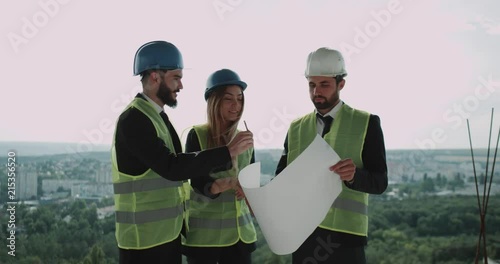 Construction supervisor stand on the rooftop looking at plan of the building. photo