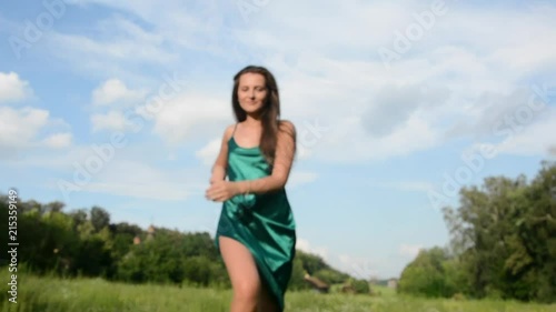 Beautiful happy young woman in a summer dress and in a whirls, turn around at the rural landscape background