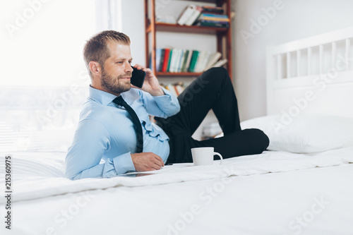 Businessman working from a hotel room with his mobile phone