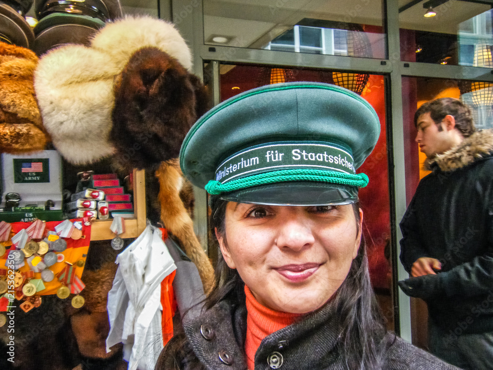 Fototapeta premium Touristin in Berlin mit Stasi Mütze vor Souvenirladen